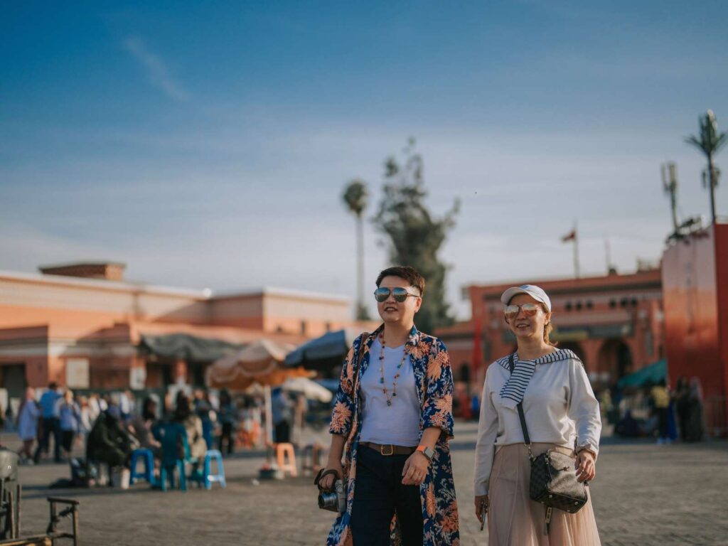 Tourists exploring a busy square in Marrakech during the day