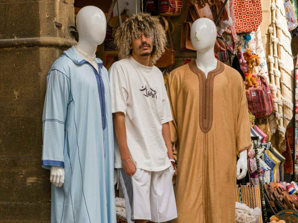 Man standing in a Moroccan souk wearing traditional and casual clothing