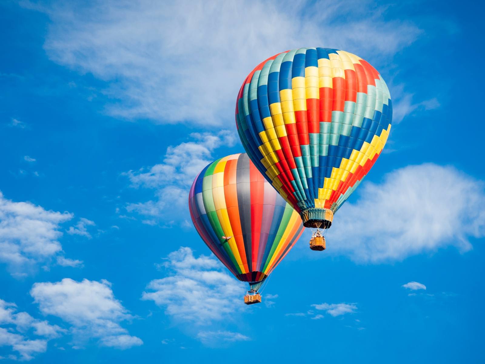 Marrakech deals: Two colorful hot air balloons floating in a bright blue sky with scattered clouds