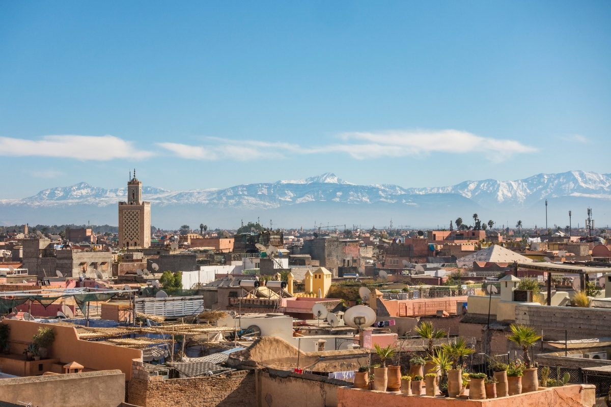 Morocco travel tips guide featuring Marrakech medina skyline and Atlas Mountains